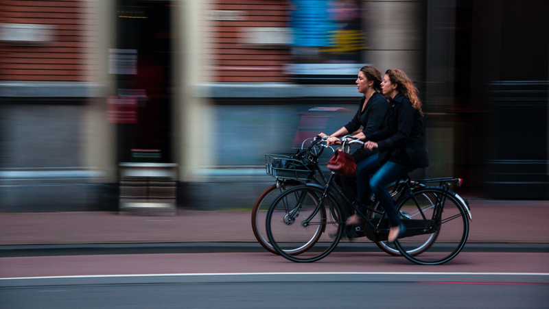 Två kvinnor som cyklar i en stad.