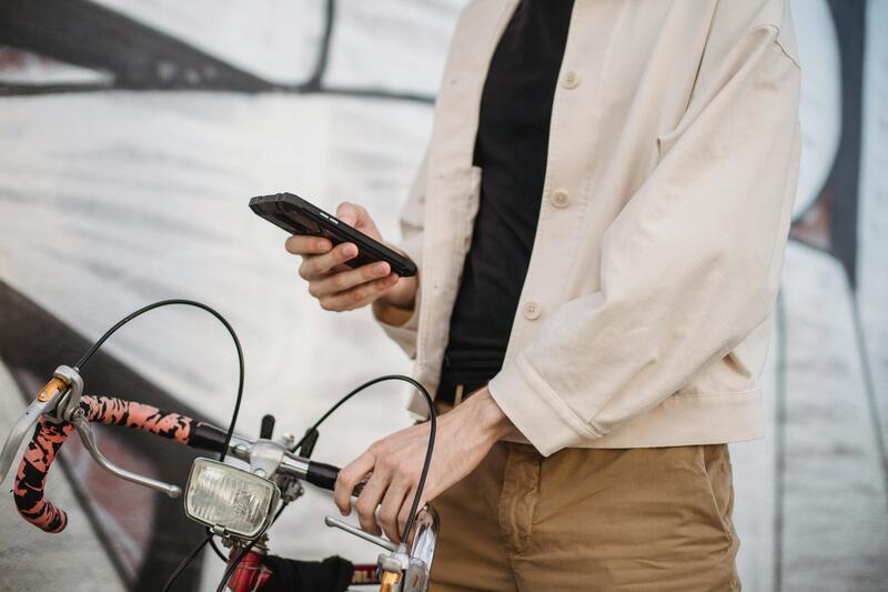 En person som håller i sin cykel och samtidigt tittar på sin mobiltelefon