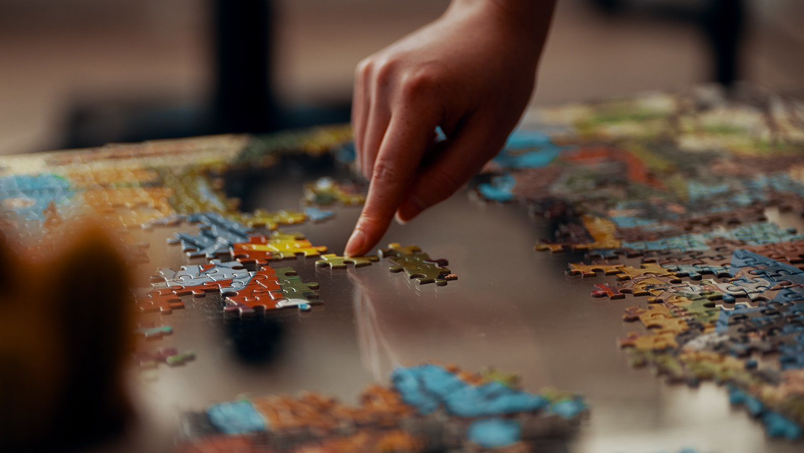 Someone laying a puzzle. Photo: Ross Sneddon on Unsplash.